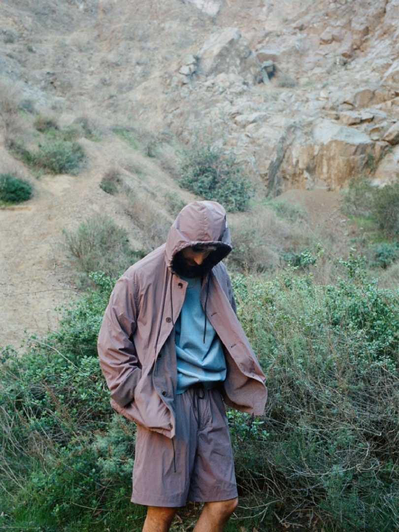 Rel wears Terry Lined Light Nylon Blouson in Light Brown, Super High Gauge Cotton Knit P/O in Blue, Terry Lined Light Nylon Easy Shorts in Light Brown