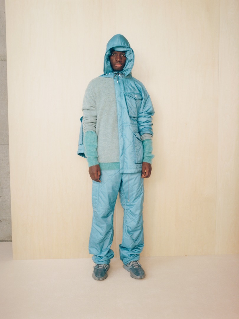 Mamadou wears Quilted Super Light Nylon Ripstop Field Blouson in Blue, Quilted Super Light Nylon Ripstop Field Pants in Blue, Shetland Wool Cashmere Knit P/O in Top Blue Green