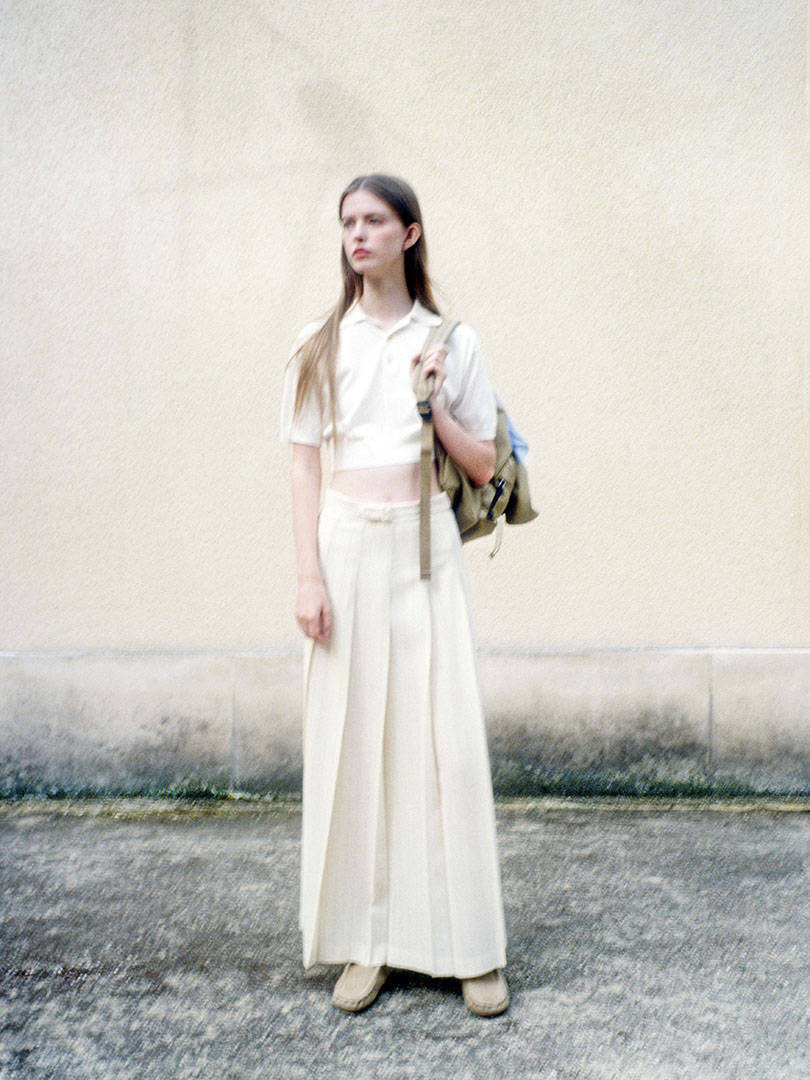 Charlotte wears Super High Gauge Washable Silk Knit Short Polo in Ivory White, Hard Twist Wool Panama Stripe Pleated Skirt in Ivory Stripe