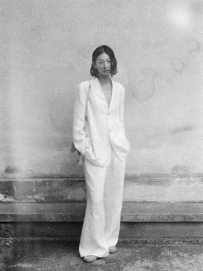 Hsiang wears Linen Gabardine No Collar Jacket in Ivory White, Linen Gabardine Slacks in Ivory White