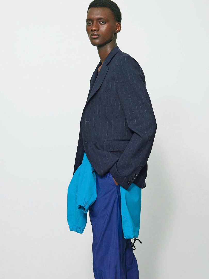 Bangali wears Hard Twist Wool Panama Stripe Jacket in Navy Stripe, Washed Cotton Nylon Weather Easy Pants in Purple