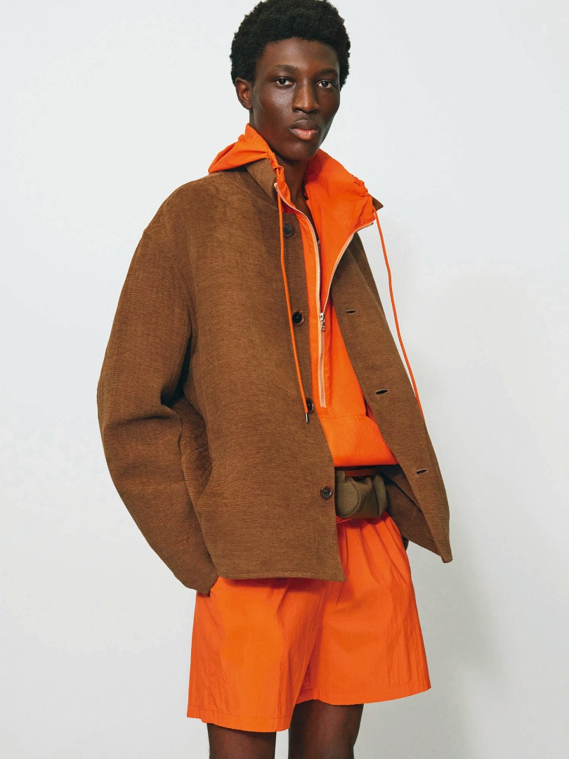 Raymond wears Cotton Mole Melton Hand Sewn Blouson in Brown, Washed Cotton Nylon Weather Hooded Zip P/O in Orange, Washed Cotton Nylon Weather Easy Shorts in Orange
